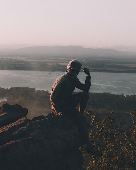 man sitting on cliff over body of water in Alabama United States