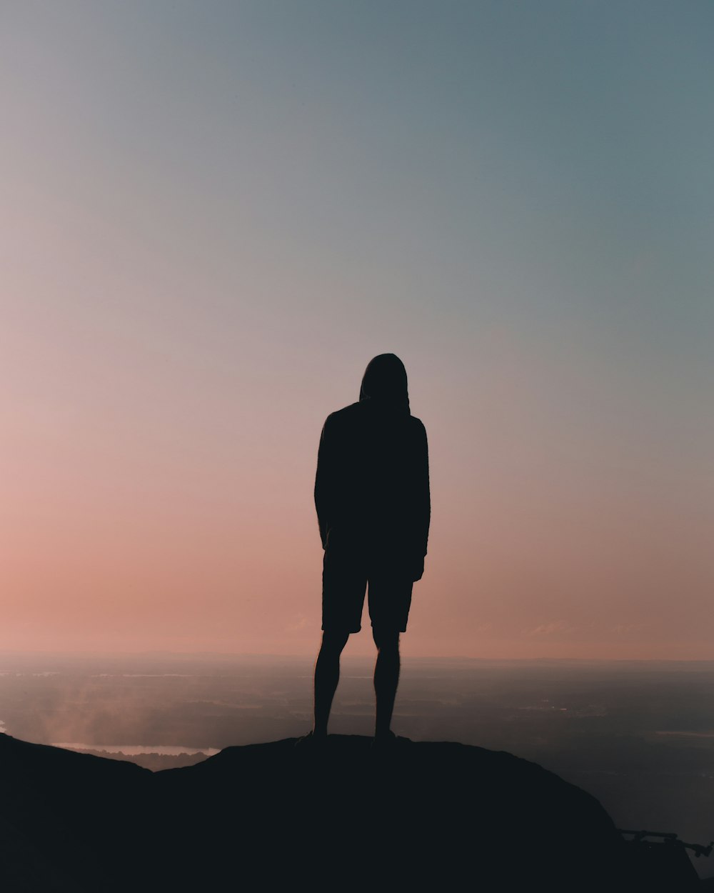 silhouette man standing on mountain under gray sky