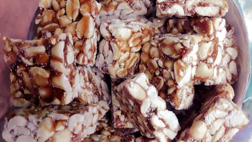 Slices of rich, buttery peanut brittle catching the light on a vintage ceramic plate.