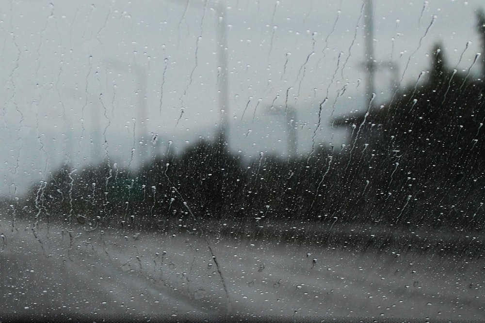 une vue d’une rue à travers une fenêtre couverte de pluie