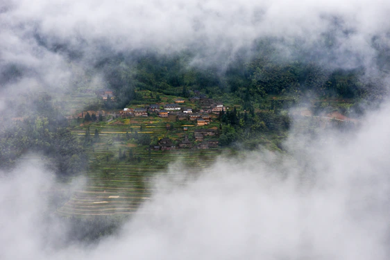 A serene village scene at dawn with villagers tending to fields and children playing near a traditional temple.