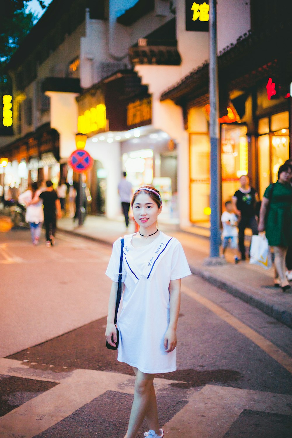 woman wearing white dress standing on road between stores