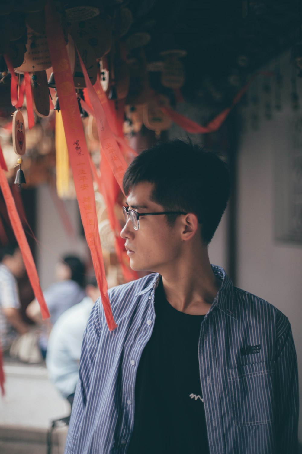 a man wearing glasses standing in front of red streamers