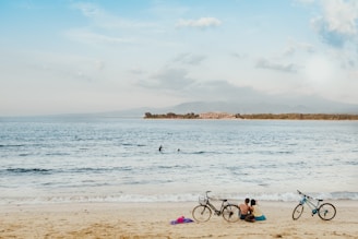 A tranquil beach scene with bicycles on the sand.