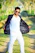 A confident man wearing a sleek, modern jacket from Invisible Boutique, smiling outdoors in soft natural light.