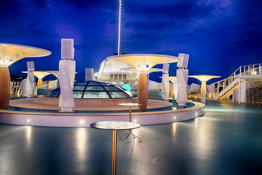 Guests enjoying a gourmet dinner on the deck of a cruise ship under a starry sky.