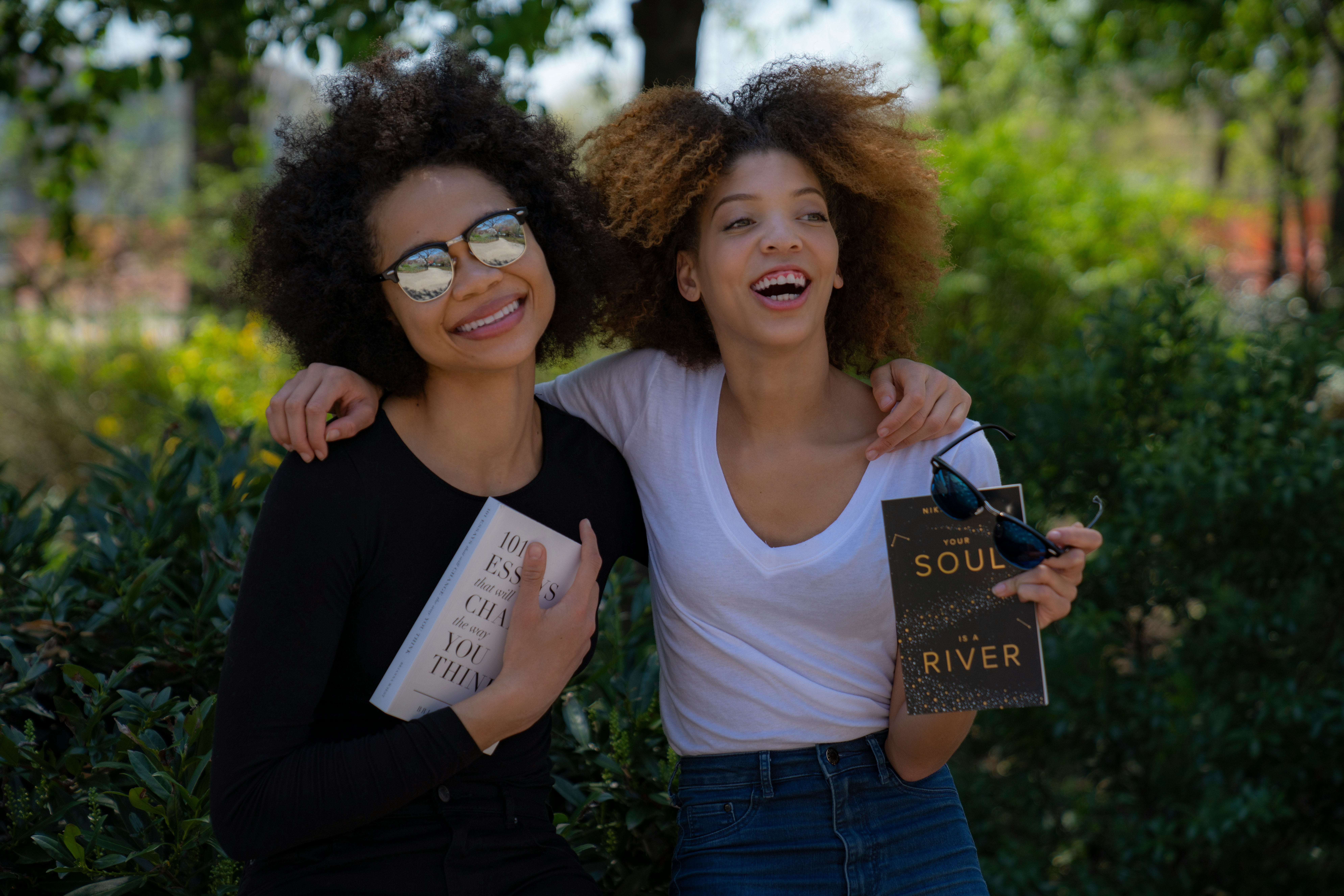 two smiling women while holding novel books