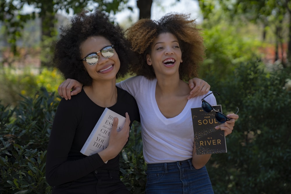 two smiling women while holding novel books