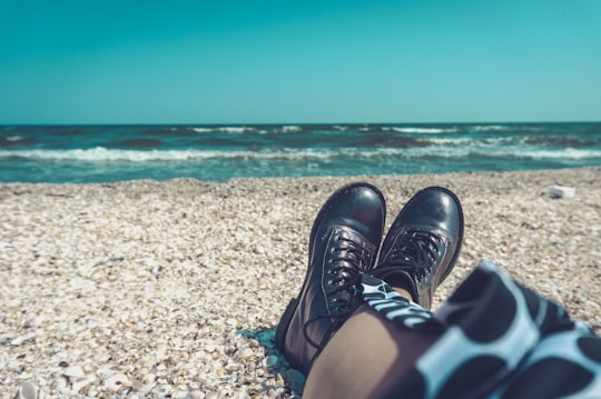 person wearing pair of black leather shoes sitting on seashore in Mamaia Romania