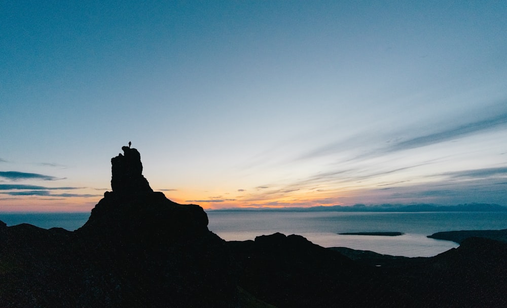 silhouette of hill and body of water during daytime