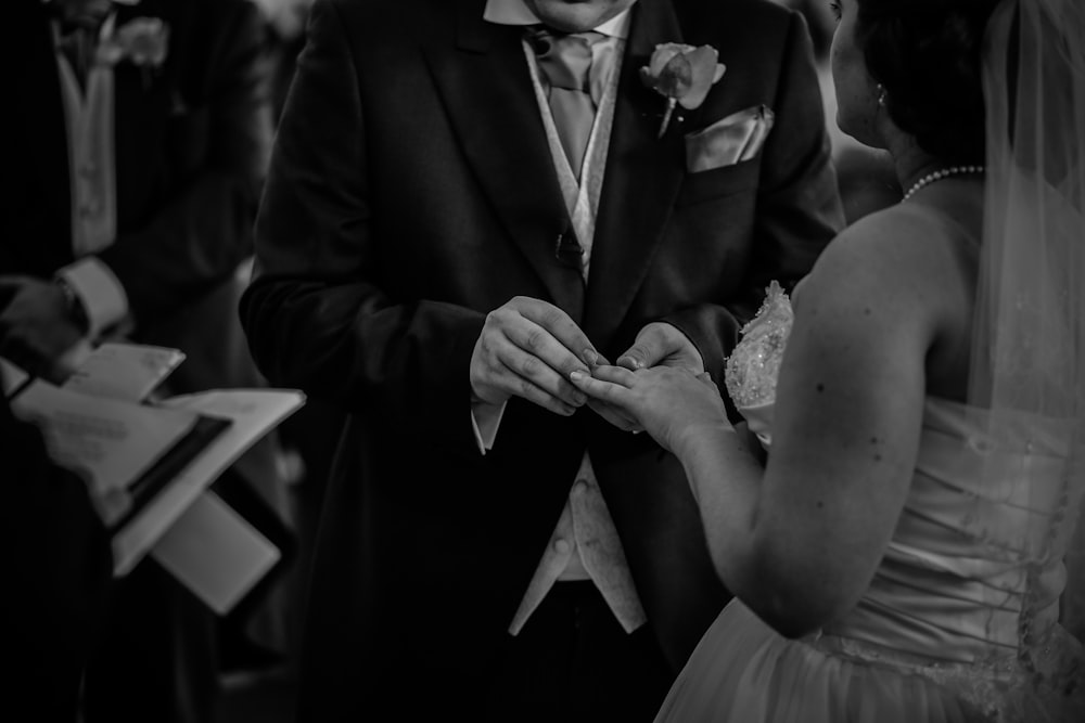 a man in a suit and tie putting a ring on a woman's finger