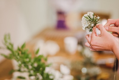 Close-up of hands gently holding a small memorial flower arrangement.