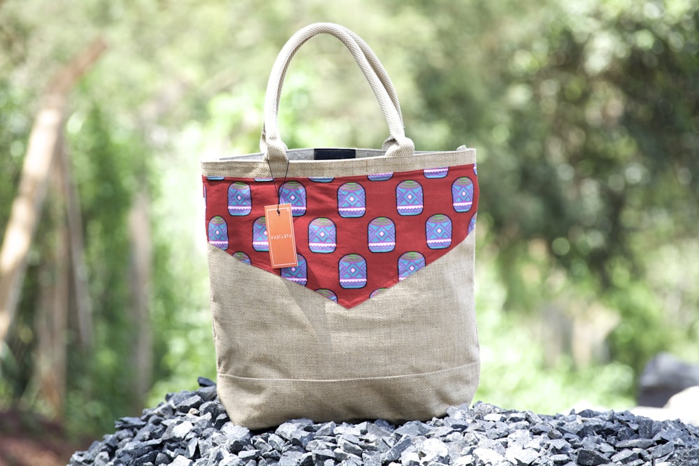 women's brown and red leather tote bag on top of gravel