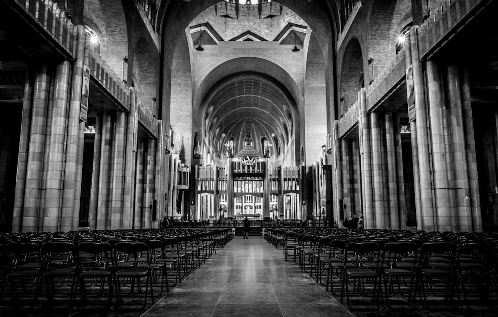 grayscale photo of man standing in front of altar