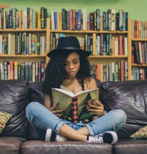 woman reading a book while sitting on black leather 3-seat couch