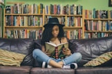 woman reading a book while sitting on black leather 3-seat couch