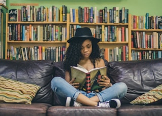 woman reading a book while sitting on black leather 3-seat couch