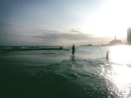 Sunlit beach scene with a model wearing vibrant tropical beachwear by arantzabeach, waves gently rolling in the background.