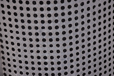 Perforated metal sheet with uniform round holes, displayed on a workshop table.