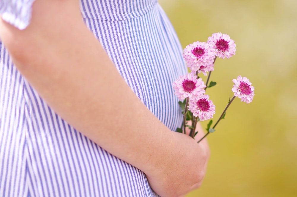 mulher gravida segurando flores de pétalas
