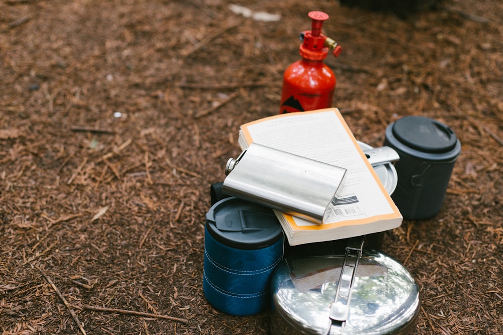 flat lay photography of hip flask, book, tiffin carrier and container
