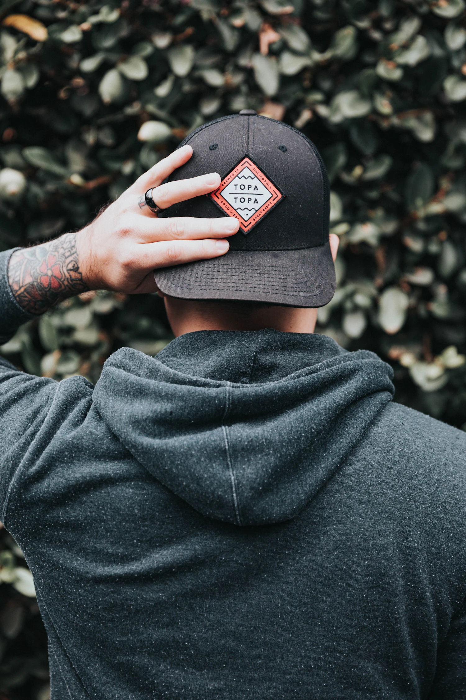 Man in a black cap and grey hoodie, seen from behind