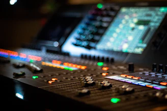 Close-up of a microphone and mixing console with curved sound waves visualized in the background.