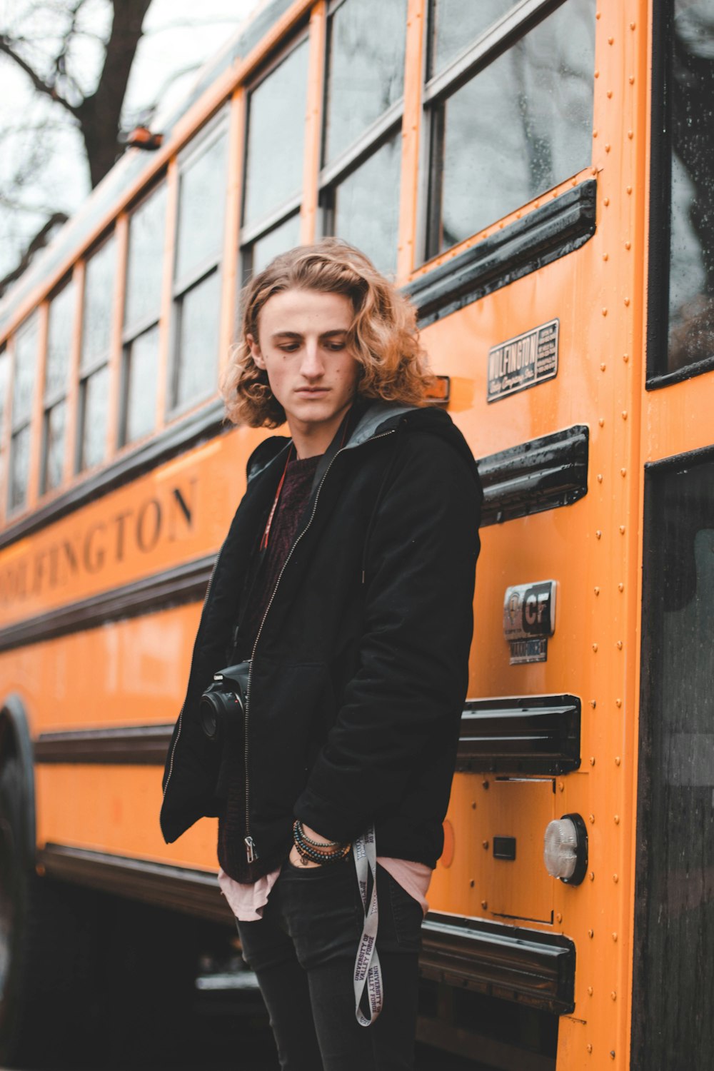 man in black zip-up jacket standing beside bus