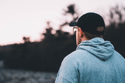 man wearing blue hoodie and black hat cap google meet background