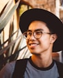 smiling man wearing black framed eyeglasses and hat