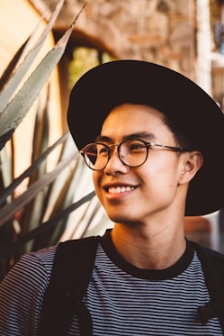 smiling man wearing black framed eyeglasses and hat