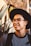 smiling man wearing black framed eyeglasses and hat