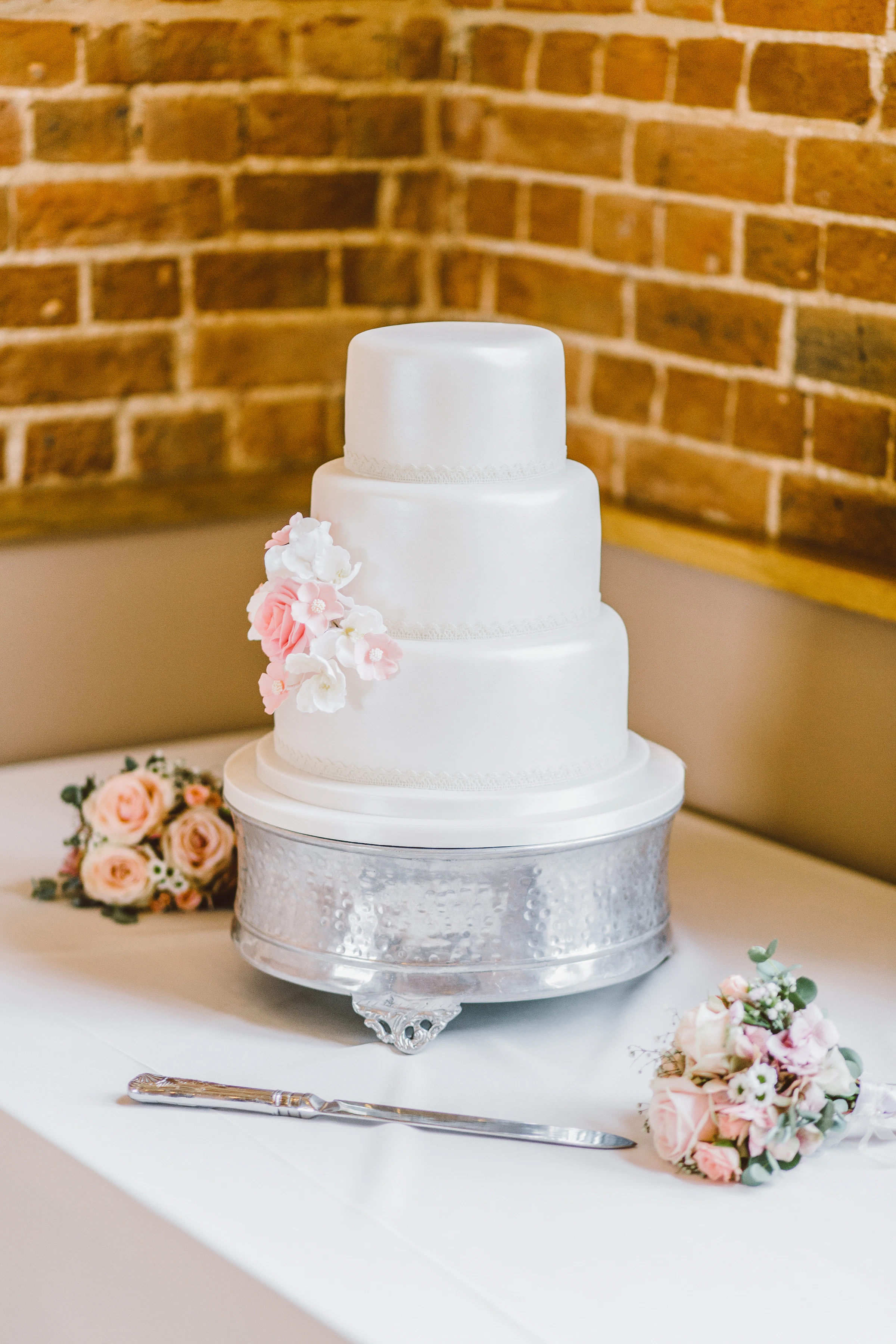 Pastel de boda de tres niveles rodeado de arreglos florales
