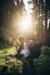 man taking a squat and taking a photo of grass at golden hour