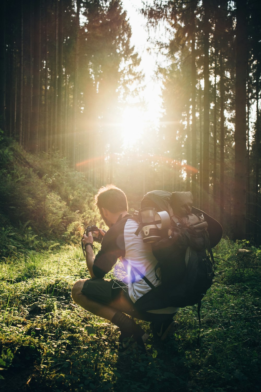 man taking a squat and taking a photo of grass at golden hour