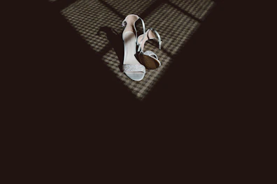 A pair of stylish high-heeled shoes placed on a marble floor with a subtle shadow.
