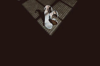 A pair of stylish high-heeled shoes placed on a marble floor with a subtle shadow.