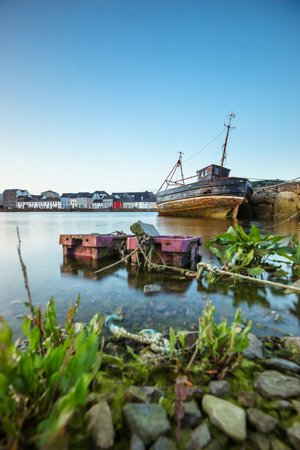 brown and gray ship on water near village under blue sky