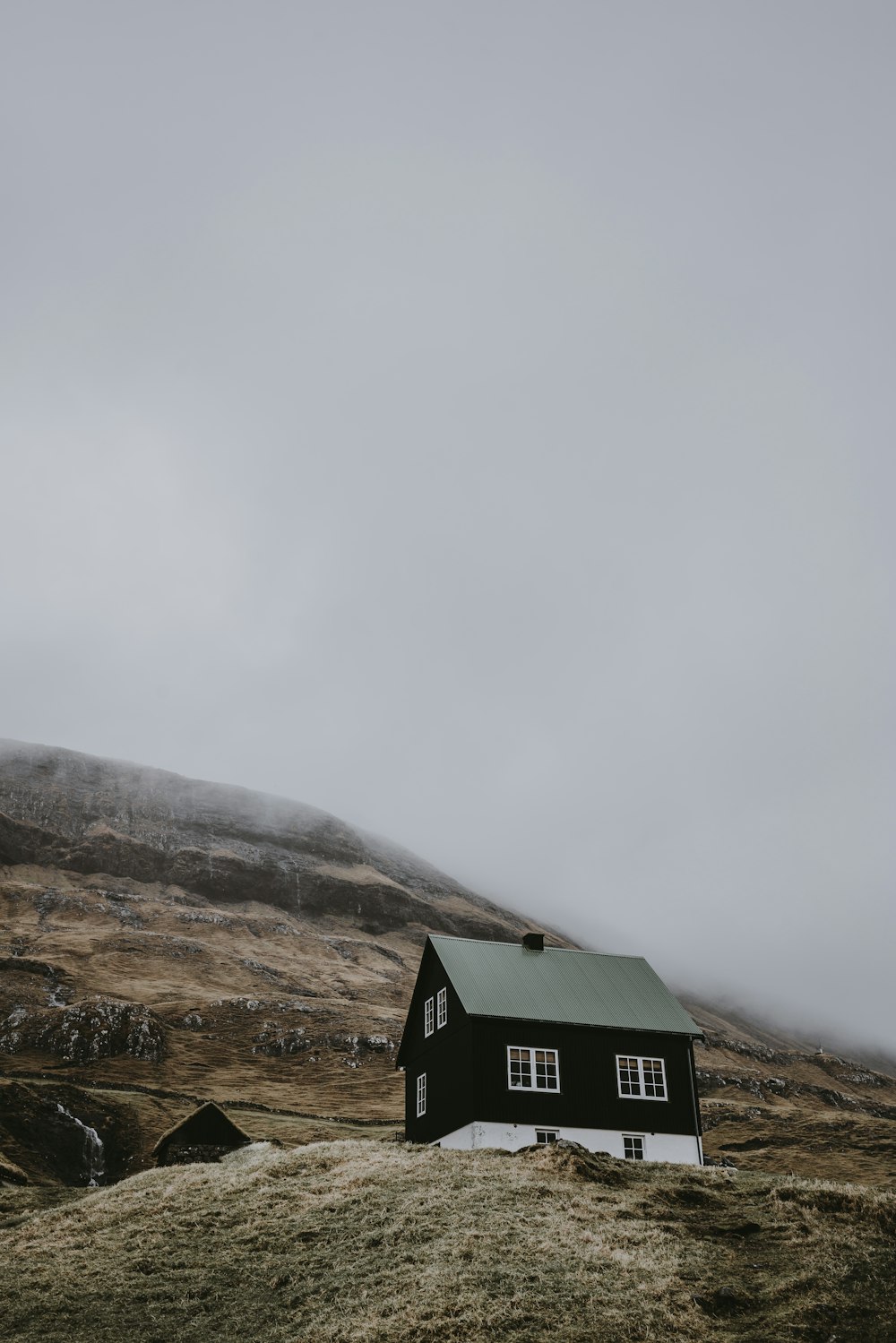 Casa de madeira preta e branca no topo da colina