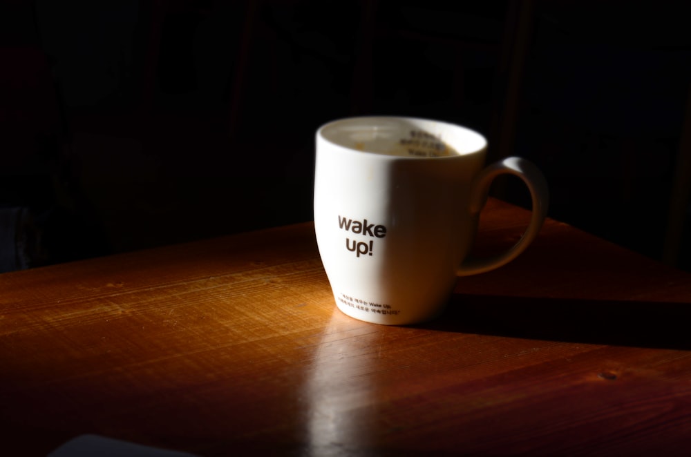 Foto de primer plano de taza blanca sobre superficie de madera