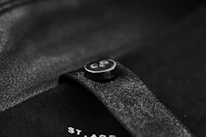 Close-up of elegant black ghost-style button with white border on a sleek dark background.