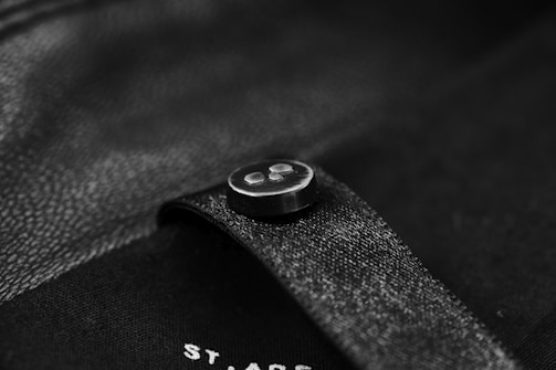 Close-up of a finely textured black silk blouse with subtle rose gold buttons reflecting soft light.