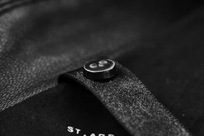 Close-up of elegant black ghost-style button with white border on a sleek dark background.