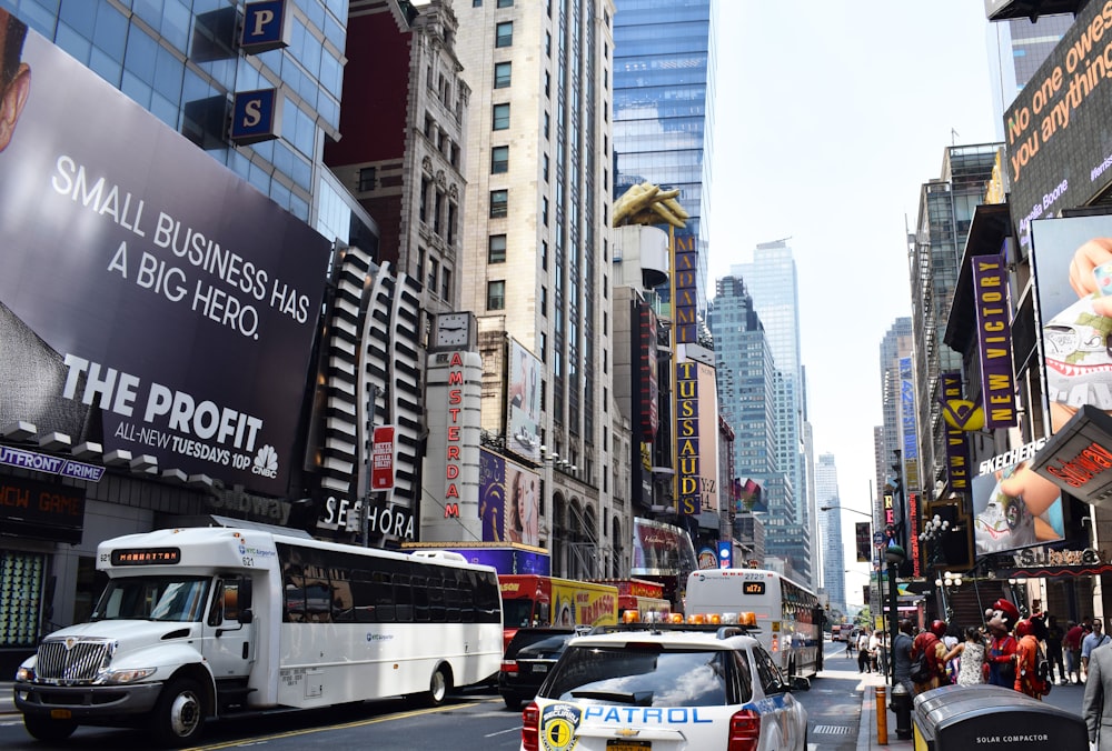 white and black bus on road near high rise buildings during daytime