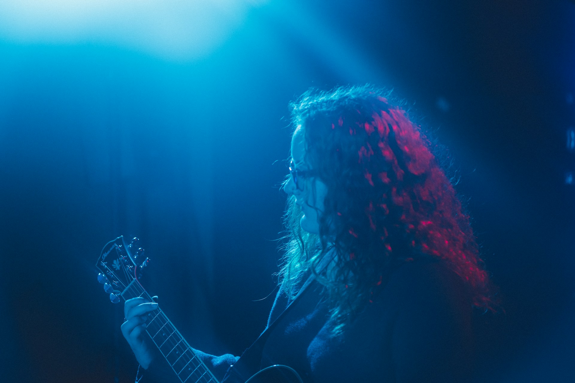 A dynamic shot of a soulful blues guitarist mid-performance, fingers bending strings under moody blue stage lights.