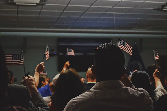 A warm, inviting photo of a local community meeting with American flags displayed.
