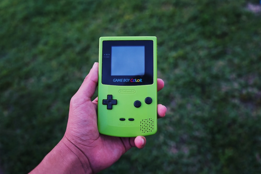 persona sosteniendo una consola de color verde Gameboy