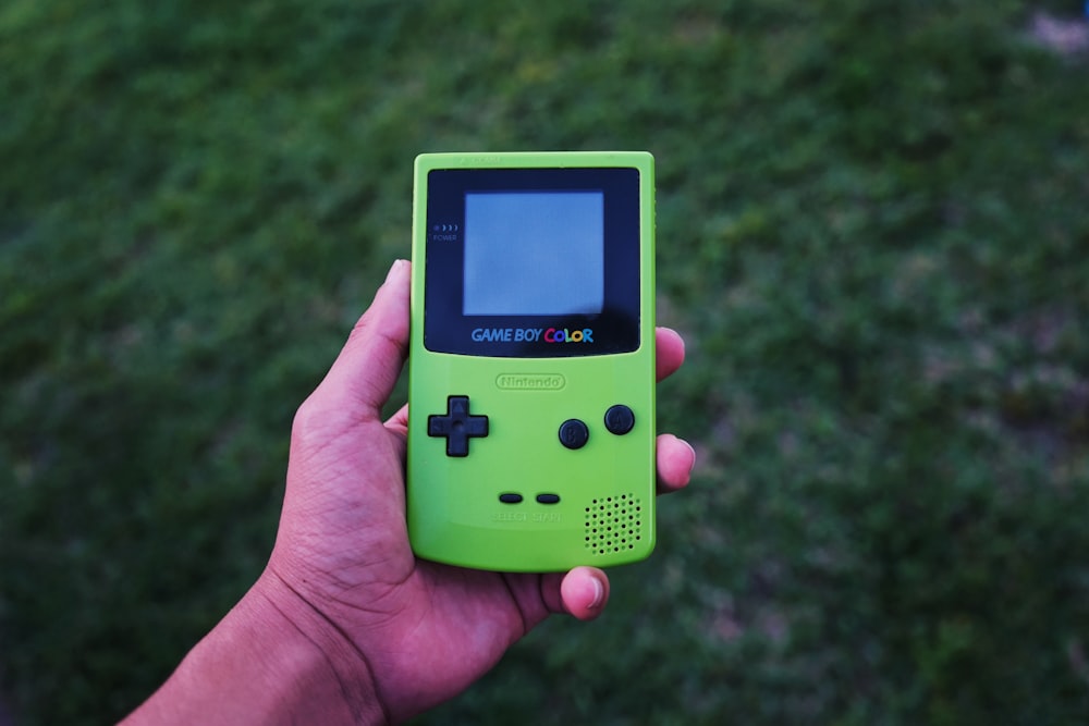 persona che tiene una console di colore Gameboy verde