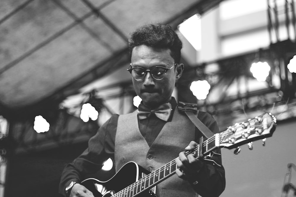 greyscale photo of man playing guitar