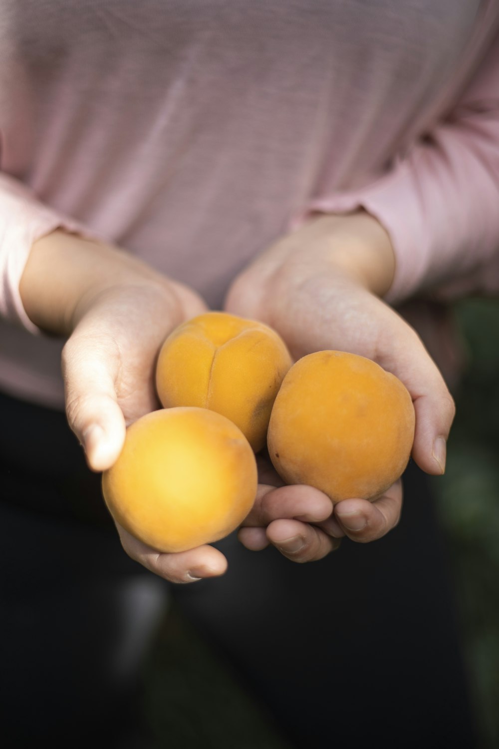 Person mit drei runden orangefarbenen Früchten